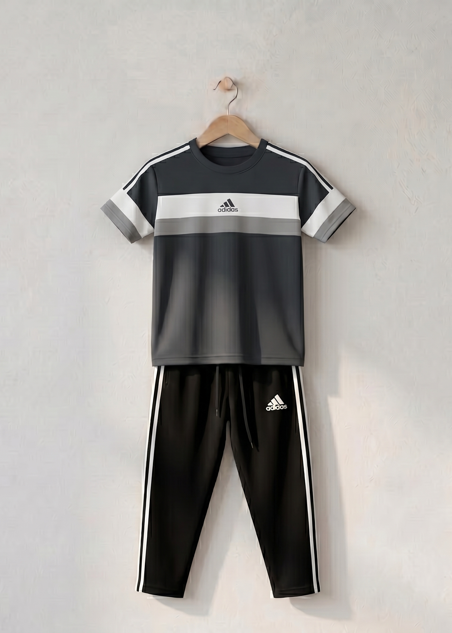 Black and gray children's tracksuit on a wooden hanger against a light gray background